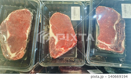 Packaged raw beef steaks on display in a supermarket refrigerator. 140669194