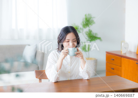 リビングでコーヒーを飲む若い女性 リビングでコーヒーを飲む若い女性 140669887