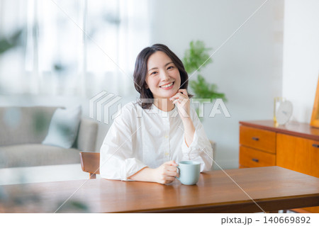 リビングでコーヒーを飲む若い女性 リビングでコーヒーを飲む若い女性 140669892
