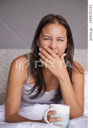 Woman, yawn or coffee in bed for energy to wake up in peace, morning routine for mental health. Tired, sleepy or female person in cozy, comfort or warm for tea as soothing, self care or stress relief Woman, yawn or coffee in bed for energy to wake up in peace, morning routine for mental health. Tired, sleepy or female person in cozy, comfort or warm for tea as soothing, self care or stress relief 140670181