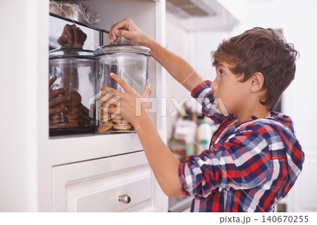 Cookies, kitchen and snack for boy in house for steal, sneaky or sugar in pantry or cupboard for meal. Young person or kid with hand in jar for biscuit, sweet or naughty for wrong or childhood 140670255