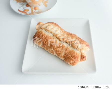 Freshly baked pastry on white plate with coffee cup in background Freshly baked pastry on white plate with coffee cup in background 140670260