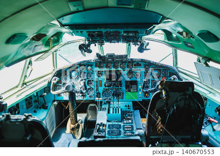 Pilot cockpit of a large aircraft showing control panels and instruments during daylight 140670553