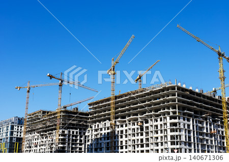 High-rise concrete building construction site with tower cranes under clear blue sky High-rise concrete building construction site with tower cranes under clear blue sky 140671306