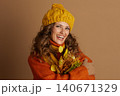 Smiling Woman in Autumn Scarf and Hat with Leaves Smiling Woman in Autumn Scarf and Hat with Leaves 140671329