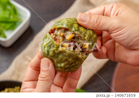 hands breaking open a steamed sticky multi-grain bun showing rich bean and corn filling hands breaking open a steamed sticky multi-grain bun showing rich bean and corn filling 140671659