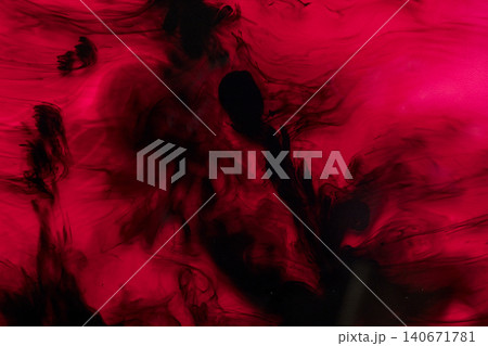 An abstract close-up of dark black ink dissolving and swirling in vibrant red liquid, creating fluid smoke-like patterns An abstract close-up of dark black ink dissolving and swirling in vibrant red liquid, creating fluid smoke-like patterns 140671781