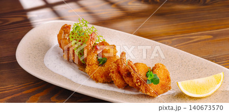 Fried breaded shrimp with sauce and lemon on wooden table Fried breaded shrimp with sauce and lemon on wooden table 140673570