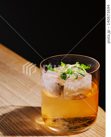 Whiskey old fashioned cocktail with large ice cube on wooden bar Whiskey old fashioned cocktail with large ice cube on wooden bar 140673694