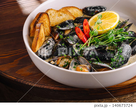 Black mussels in white wine sauce with lemon and bread 140673724