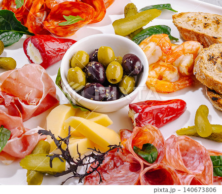 Appetizer platter presenting cured meats, cheese, olives and shrimp Appetizer platter presenting cured meats, cheese, olives and shrimp 140673806