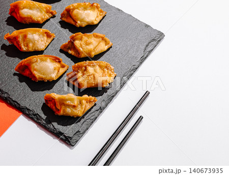 Fried gyoza dumplings on slate board with chopsticks Fried gyoza dumplings on slate board with chopsticks 140673935