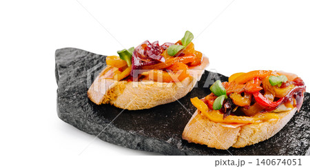 Bruschetta tapas with roasted peppers and prosciutto on slate Bruschetta tapas with roasted peppers and prosciutto on slate 140674051