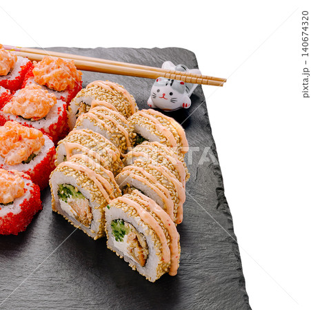 Sushi rolls with sesame seeds, sauce, and tobiko on slate Sushi rolls with sesame seeds, sauce, and tobiko on slate 140674320