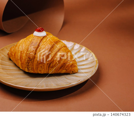 Croissant with cream and cherry on plate Croissant with cream and cherry on plate 140674323
