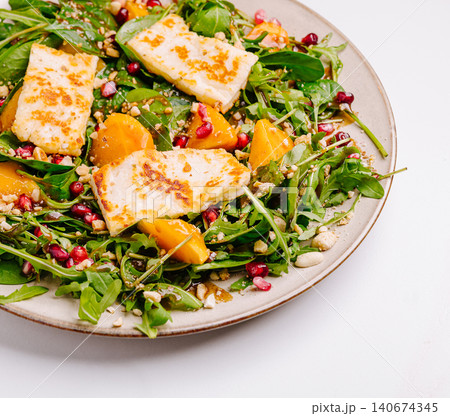 Halloumi salad with arugula, pomegranate, and persimmon Halloumi salad with arugula, pomegranate, and persimmon 140674345