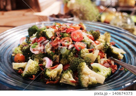 Fresh broccoli salad with tomatoes and red pepper in black plate Fresh broccoli salad with tomatoes and red pepper in black plate 140674373
