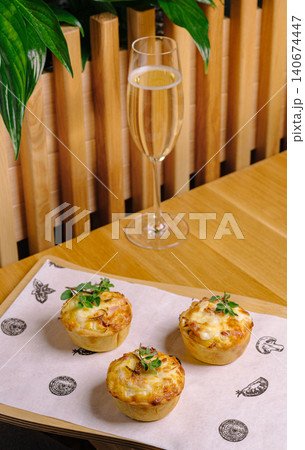 Savory mini quiche tartlets and sparkling wine glass on wooden table Savory mini quiche tartlets and sparkling wine glass on wooden table 140674447