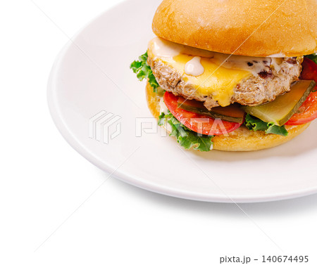 Cheeseburger with beef patty, melted cheese, and vegetables on white plate 140674495