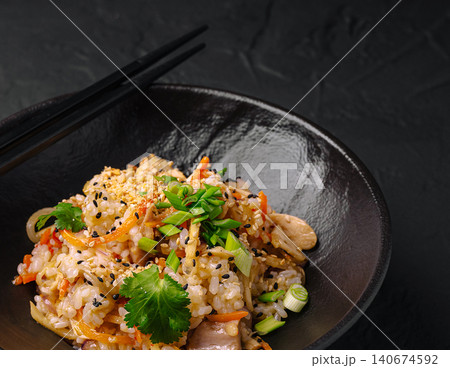 Fried rice with vegetables and chopsticks in black bowl Fried rice with vegetables and chopsticks in black bowl 140674592