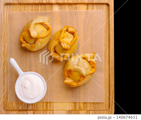 Steaming dumplings on parchment paper with sour cream 140674631