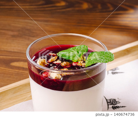 Panna cotta dessert with berry sauce, nuts, and mint Panna cotta dessert with berry sauce, nuts, and mint 140674736