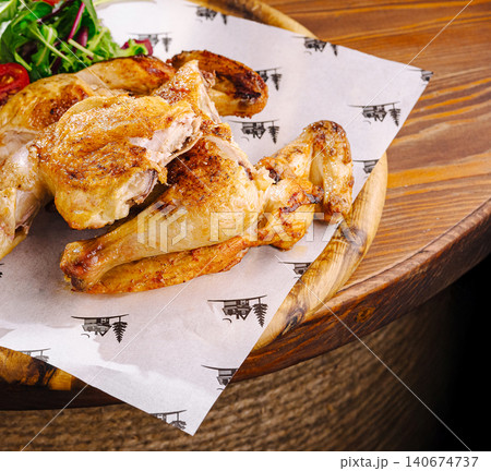 Golden brown roasted chicken with fresh salad on wooden platter Golden brown roasted chicken with fresh salad on wooden platter 140674737