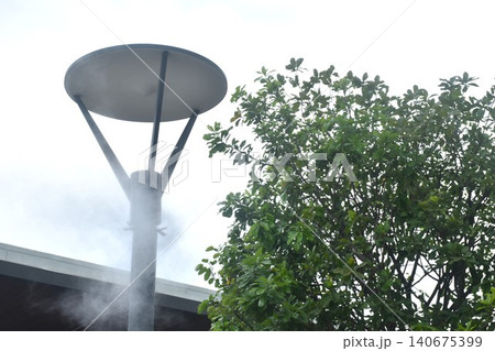 outdoors misting post light for spraying fog to cool air down and blowing pm 2.5 dust away and lighting in night at garden 140675399