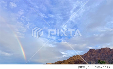 Rainbow over Desert Mountains under Cloudy Blue Sky Rainbow over Desert Mountains under Cloudy Blue Sky 140675645