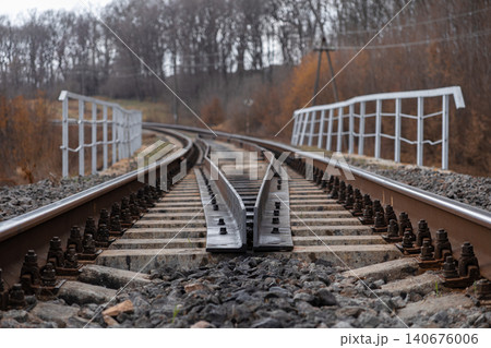 Railway track switch diverging into the distance on a bridge, capturing the industrial perspective and classic geometric lines of transportation infrastructure in autumn forests 140676006