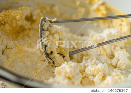 Cottage cheese being mashed with a metal tool in a bowl to create a smooth texture, capturing a practical cooking preparation process for a healthy homemade meal or dairy snack Cottage cheese being mashed with a metal tool in a bowl to create a smooth texture, capturing a practical cooking preparation process for a healthy homemade meal or dairy snack 140676367