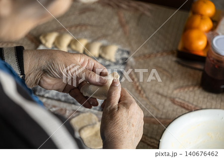 Elderly person manually shaping handmade dumplings on a tabletop, emphasizing traditional culinary practices, cultural heritage, home cooking, and the art of preparing authentic food Elderly person manually shaping handmade dumplings on a tabletop, emphasizing traditional culinary practices, cultural heritage, home cooking, and the art of preparing authentic food 140676462