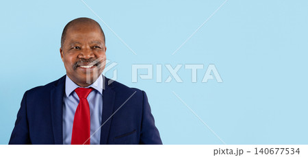 Smiling mature African American businessman in suit and tie on blue background Smiling mature African American businessman in suit and tie on blue background 140677534