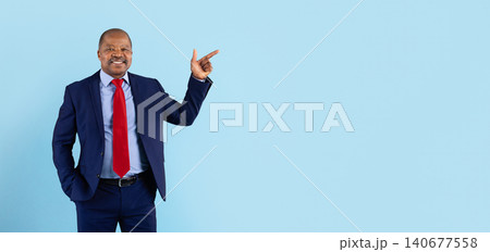 Mature African American businessman in suit pointing upward toward empty copy space Mature African American businessman in suit pointing upward toward empty copy space 140677558