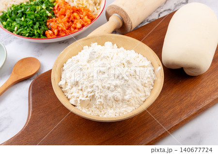 White wheat flour in bowl with dough and rolling pin for making Chinese dumplings White wheat flour in bowl with dough and rolling pin for making Chinese dumplings 140677724