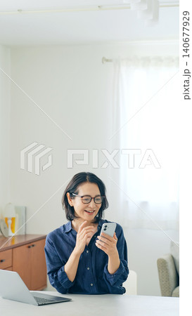 スマホを見ながら喜ぶミドル女性 140677929