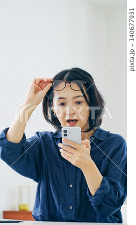 スマホを見ながら悩むミドル女性 スマホを見ながら悩むミドル女性 140677931