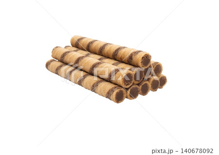 Close up photo of cylindrical wafer rolls filled with chocolate cream, arranged in a pyramid formation on a white background. Close up photo of cylindrical wafer rolls filled with chocolate cream, arranged in a pyramid formation on a white background. 140678092