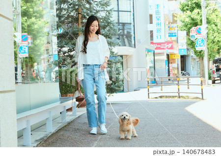 夏の街中で愛犬と散歩する笑顔の若い女性 夏の街中で愛犬と散歩する笑顔の若い女性 140678483