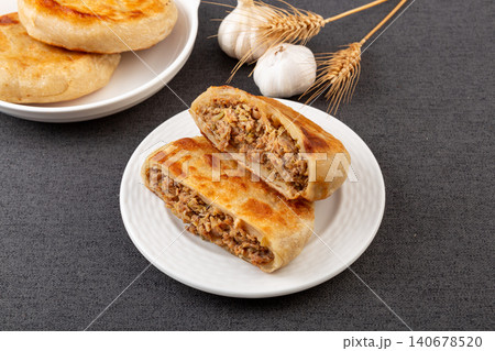 A row of golden fried meat pies served on a long ceramic plate against a dark background. A row of golden fried meat pies served on a long ceramic plate against a dark background. 140678520