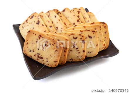 A heap of rectangular cranberry butter cookies with dried fruit bits scattered on a white background. A heap of rectangular cranberry butter cookies with dried fruit bits scattered on a white background. 140678543