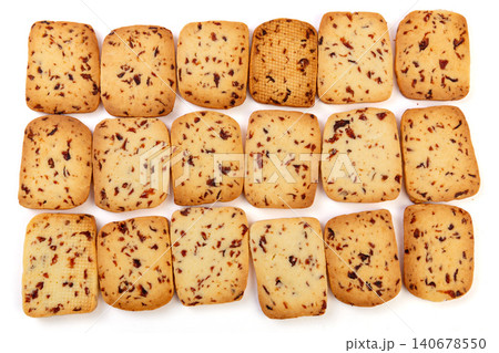 A heap of rectangular cranberry butter cookies with dried fruit bits scattered on a white background. A heap of rectangular cranberry butter cookies with dried fruit bits scattered on a white background. 140678550