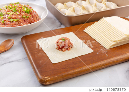 Raw Meat Filling on Square Wonton Wrapper on Cutting Board, Dumpling Making Process 140678570