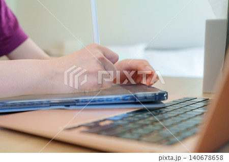 Focused student engaging in online learning with digital tablet and laptop at home for enhanced study experience Focused student engaging in online learning with digital tablet and laptop at home for enhanced study experience 140678658