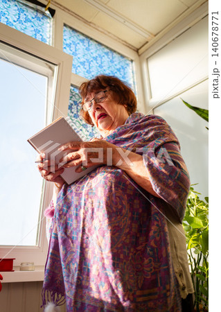 Caucasian elderly woman composing thoughtful notes near a window in a cozy interior. Learning and productive leisure. Senior education concept. Vertical Caucasian elderly woman composing thoughtful notes near a window in a cozy interior. Learning and productive leisure. Senior education concept. Vertical 140678771