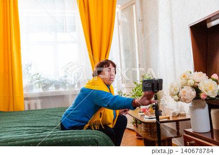 Senior Caucasian female presenting decorative cosmetics during a live broadcast from a comfortable home interior. Beauty blogging and content creation concept. Modern retirement 140678784