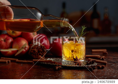 Apple kombucha is poured from a bottle into a crystal glass. 140678989