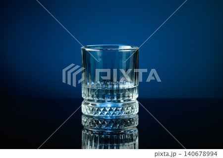Glass of vodka on a black reflective background, with blue lighting. Glass of vodka on a black reflective background, with blue lighting. 140678994