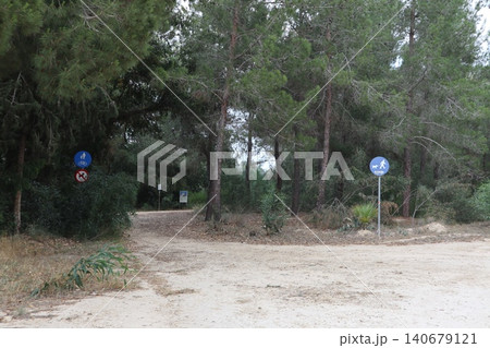 Prohibitory and information signs in a public park. Dirt path through a forest of trees. Prohibitory and information signs in a public park. Dirt path through a forest of trees. 140679121
