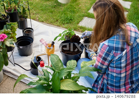 Woman adding soil to plant pot on terrace Woman adding soil to plant pot on terrace 140679288